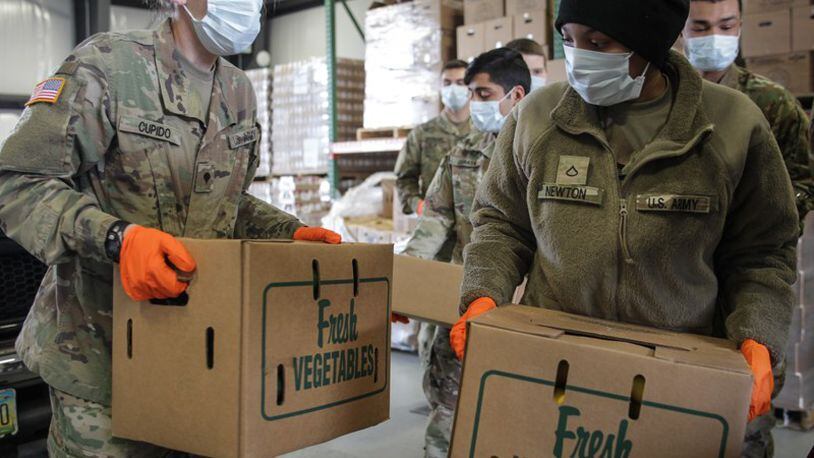 Ohio National Guard members help load food into trunks at The Foodbank at 56 Armor Place in Dayton. STAFF/JIM NOELKER