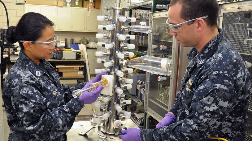 Navy Lts. Dan Xu (left), a Navy research biochemist, and Joshua Roaf (right), a Naval surface warfare officer and graduate intern on site at Naval Medical Research Unit-Dayton as part of his master s program in toxicology at the University of North Carolina at Chapel Hill, work to draw a filter sample for contaminant verification of particulate matter during a test at NAMRU-D s Environmental Health Effects Laboratory July 25. (U.S. Air Force photo/Bryan Ripple).