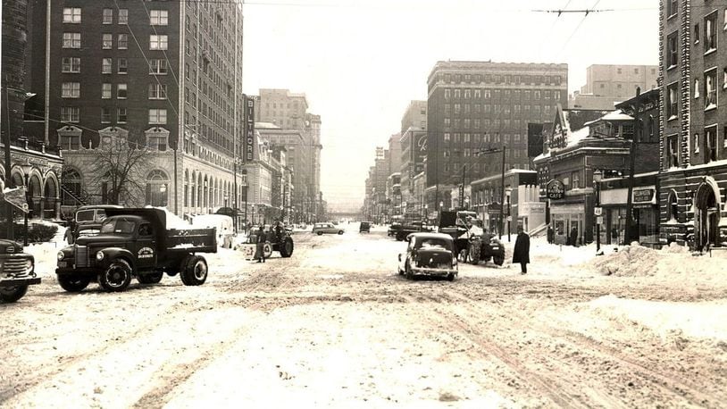 Vehicles and pedestrians attempt to navigate Main St. in downtown Dayton after nearly a foot of snow fell across the region after Thanksgiving Day in 1950. (Dayton Daily News File)