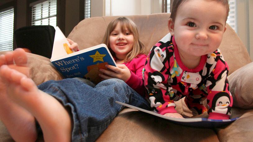 Kara McLaughlin, 5, laughs as she and her sister Kailey, 7 months, spend time with the books they received from the Dolly Parton Imaginary Library Friday afternoon, January 20, 2012 in Middletown. Children in the area who have received books from the program scored higher on tests than other students. Contributed photo by Jessica Uttinger