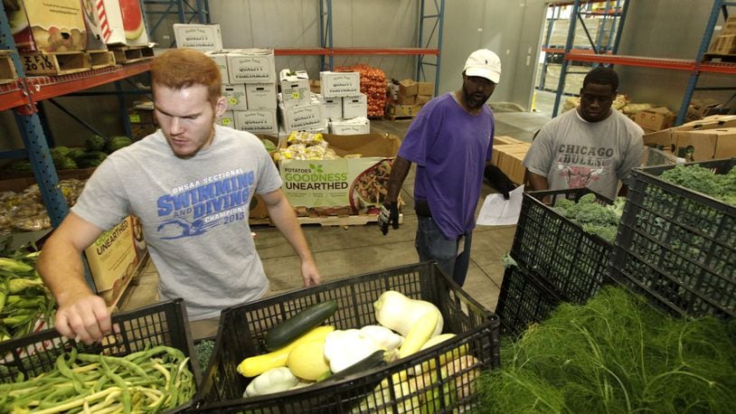 Cameron Rohrer, an employee of The Foodbank, Clark Brunson Jr., a volunteer and JaMichael Stallings, a Foodbank employee, (left to right) fill food orders to be picked up and distributed by area agencies in Dayton. Despite a decrease in the national poverty rate from 2015 to 2016, more local residents are turning to The Foodbank for assistance. LISA POWELL / STAFF PHOTO
