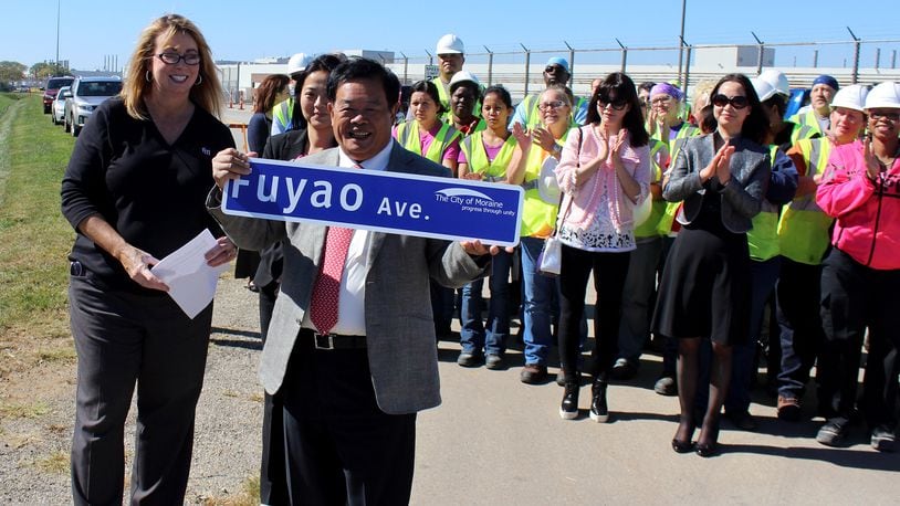 Moraine Mayor Elaine Allison and Fuyao Chairman Cao Dewang display the Fuayo Avenue street sign during dedication cerimonies in front of factory workers.
