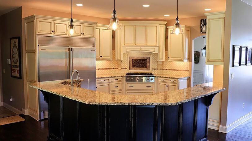 The kitchen features custom cabinetry, quilt-tile backsplash and a breakfast bar.