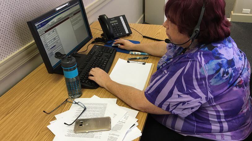 Catherine Myers, a Helplink 2-1-1 community outreach coordinator, answers phone calls this week in Dayton. BARRIE BARVER | STAFF