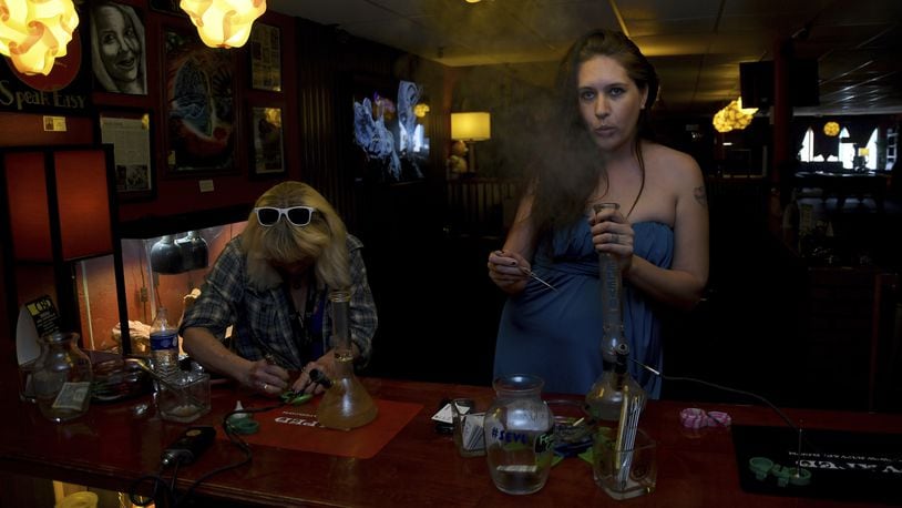 In this April, 12, 2017 photo, Alea Vigil, 34, right, smokes a concentrated form of marijuana at the Speakeasy Vape Lounge, one of the United States' only legal pot venues, in Colorado Springs, Colo. The private club serves only food and water, and no alcohol is allowed. Members have to bring their own weed and pay a membership fee of $25 a month. (AP Photo/Thomas Peipert)
