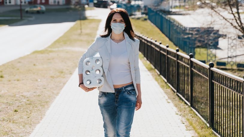 Woman walking in medical mask with toilet paper during coronavirus outbreak or covid-19. concept of covid-2019 quarantine. (Source: Shutterstock)