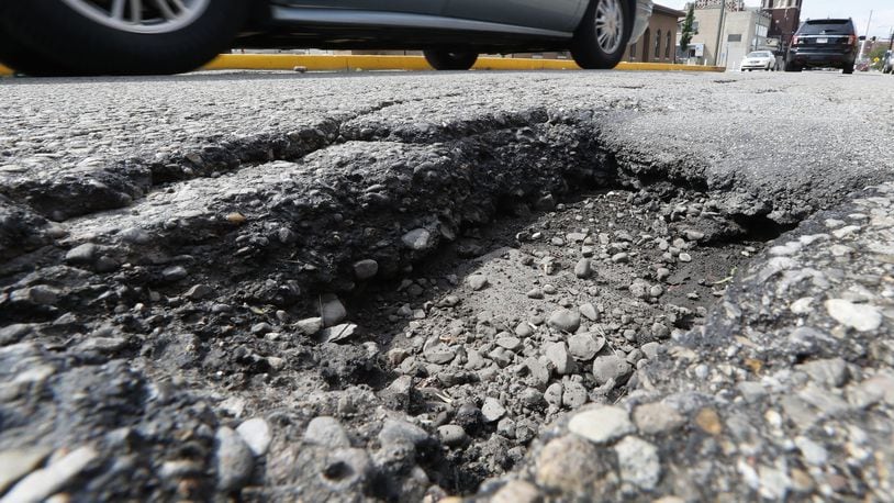 Cars drive around a pothole, several inches deep, along Center Street between Pleasant Street and North Street Friday. Bill Lackey/Staff