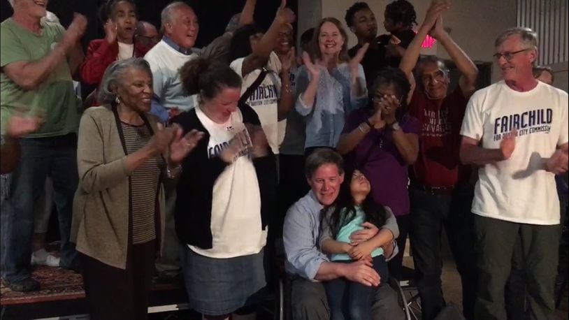 Darryl Fairchild holds his daughter, Maya, on Tuesday night as supporters celebrate Fairchild winning a seat on Dayton City Commission. JEREMY P. KELLEY / STAFF