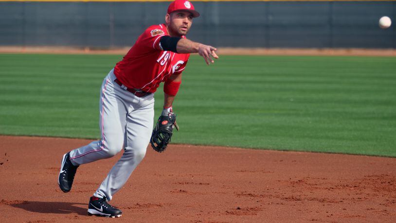 The Reds’ Joey Votto tosses a ball to first during infield drills this week in Goodyear, Ariz. MIKE HARTSOCK/STAFF