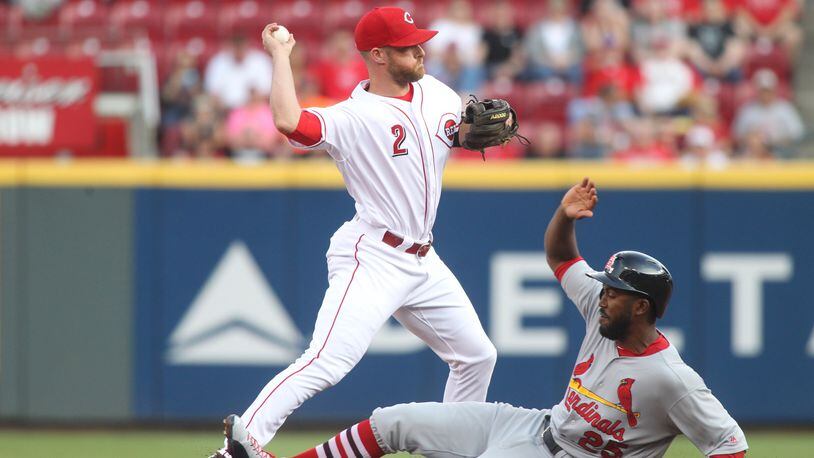 Reds shortstop Zack Cozart turns a double play as the Cardinals’ Dexter Fowler slides into second base on Monday, June 5, 2017, at Great American Ball Park in Cincinnati. David Jablonski/Staff