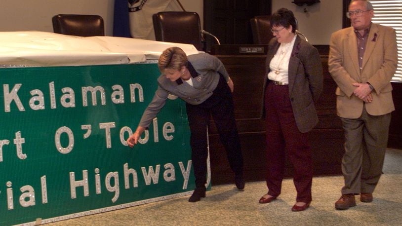 Monica O'Toole, wife of deceased former Washington Twp. firefighter Robert O'Toole, touches a sign that was hung on Interstate 675 in honor of her husband and Centerville police Officer John Kalaman. O'Toole and Kalaman were killed in January 1998 when a car slid off I-675 and struck them while they were investigating another accident. DAYTON DAILY NEWS ARCHIVE