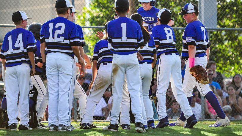 Hamilton West Side Little League’s Davis Avery is greeted by teammates at home plate after hitting one of his two home runs Monday night at West Side. The Hamilton squad beat Lebanon 10-0 to capture the District 9 tournament championship. NICK GRAHAM/STAFF