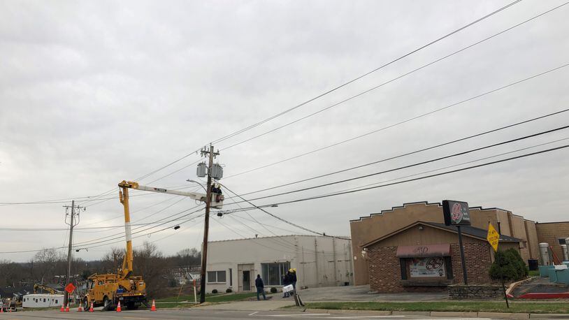 City workers adjust electric service on poles in front of two properties envisioned as part of the redevelopment of Lebanon's former city garage site.