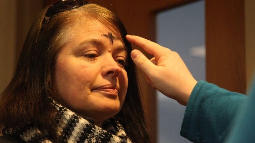 A woman receives ashes in the shape of a cross on her forehead during the Ash Wednesday ashes-to-go event at David’s United Church of Christ in Kettering. Weather forced the annual drive-through event inside. Jim Noelker / 2016 Staff File