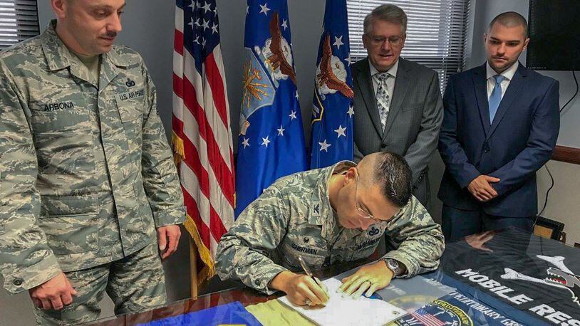 Right to left, 88th Civil Engineering Group Energy Manager Noah Fillian, Installation Planning chief Michael Tibbs, and Chief Master Sgt. Stephen Arbona, 88th Air Base Wing command chief, look on while Col. Thomas Sherman, 88th Air Base Wing and installation commander, signs an Energy Action Month proclamation to declare October 2018 as Wright-Patterson Air Force Base Energy Action Month. (U.S. Air Force photo/Stacey Geiger)