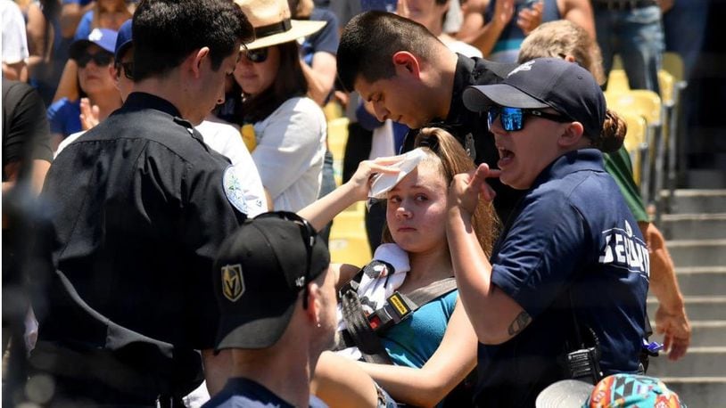 A young woman holds an ice pack to her head as she is taken by a stretcher from her seat at Dodger Stadium on Sunday. The fan was hit by a foul ball off the bat of Dodgers rightfielder Cody Bellinger.