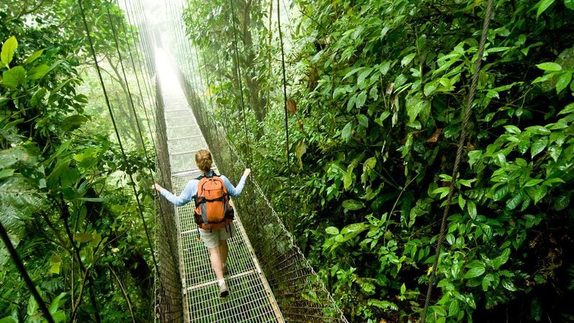 A young woman hikes along a hanging bridge near Arenal Volcano National Park in Costa Rica.