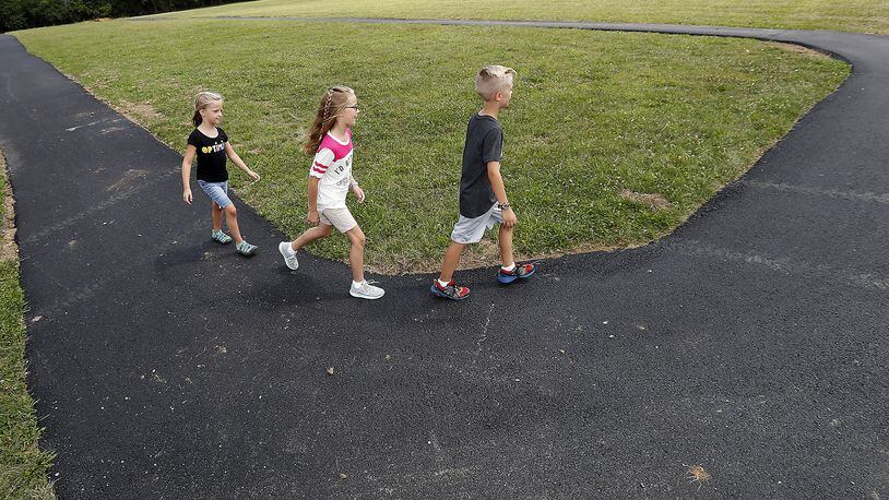 Micah, Mackenna and Jocelyn Sharbaugh walk around the new exercise track at New Carlisle Elementary Tuesday. Bill Lackey/Staff