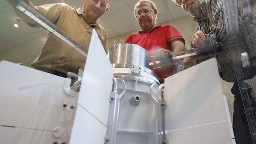 University of Dayton Research Institute scientists and engineers Chadwick Barklay, left, Daniel Kramer and Richard Harris observe a Multi-Mission Radioisotope Thermoelectric Generator that converts the heat from the natural decay of a plutonium-238 dioxide to electricity through solid-state thermoelectric couples. FILE