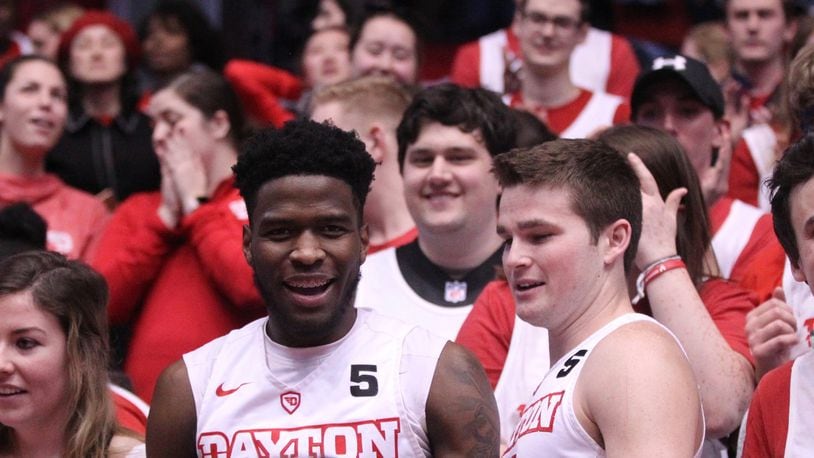 Dayton’s Jalen Crutcher and Joey Gruden celebrate with students after a victory against George Washington on Saturday, March 3, 2018, at UD Arena. David Jablonski/Staff