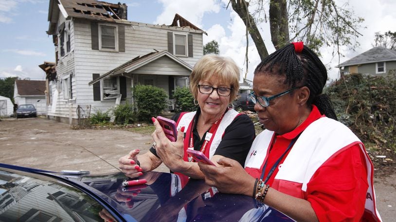 Red Cross volunteers Bonnie Russell, left, and Nadine Abdullah compare notes as the make damage assessments in Harrison Twp. after the Memorial Day tornadoes. TY GREENLEES / STAFF