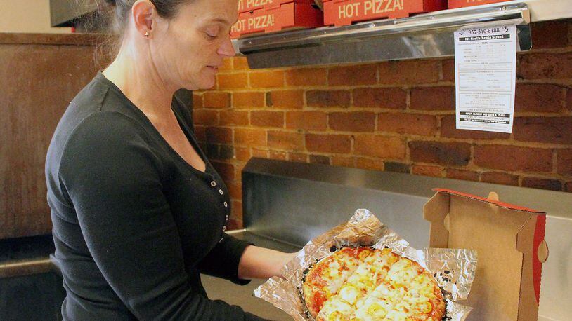 Enon Pizza & Company owner Tracy Wiggins gets ready to box up a hot pizza. JEFF GUERINI/STAFF