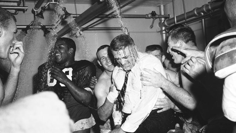 FILE - In this Nov. 16, 1957, file photo, Ohio State football coach Woody Hayes, center, gets a clothes-on dunking in the Ohio State dressing room shortly after Ohio State University won the Big Ten championship and clinched a Rose Bowl bid by defeating Iowa 17-13, in Columbus, Ohio. The Associated Press has been ranking the best teams in college football for the last 80 seasons. (AP Photo/File)