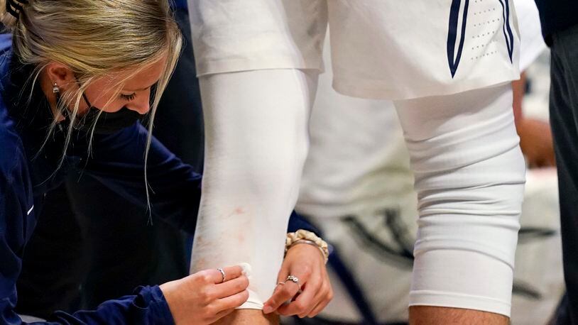 FILE - A trainer cleans blood off of the uniform of Xavier forward Jack Nunge (24) during the second half of an NCAA college basketball game against Butler, Wednesday, Feb. 2, 2022, in Cincinnati. Colleges and universities are having a difficult time hiring, recruiting and retaining members of their athletic training staffs because of a number of below-market conditions, a survey shows. (AP Photo/Jeff Dean, File)