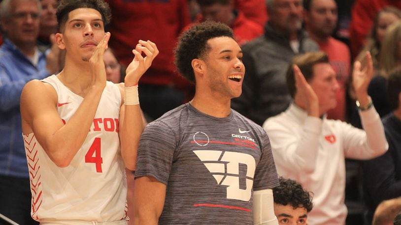 Dayton's Koby Brea, left, and Lynn Greer III cheer from the bench during a game against Virginia Tech on Sunday, Dec. 12, 2021, at UD Arena. David Jablonski/Staff