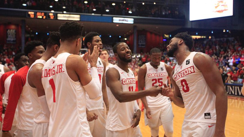 Dayton’s Scoochie Smith, center, and Josh Cunningham right, celebrate with teammates after a victory against Virginia Commonwealth on Wednesday, March 1, 2017, at UD Arena. David Jablonski/Staff