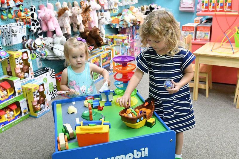 Sisters Mae Smith, 2, and Aura Smith, 3 1/2, check out some of the offerings at downtown Tipp City’s Topsy Turvy Toys. CONTRIBUTED