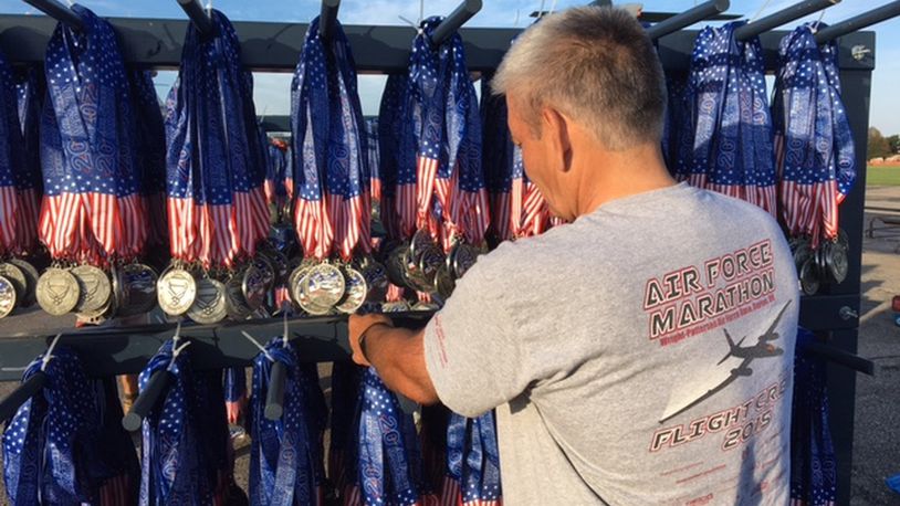 Air Force Marathon volunteer Brian Childers, of Portsmouth, hangs race day medals at the finish line at the National Museum of the U.S. Air Force in September 2016. BARRIE BARBER/STAFF FILE PHOTO