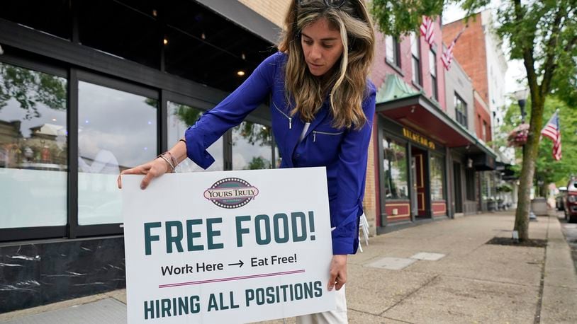 Coleen Piteo, director of marketing at Yours Truly restaurant, puts out a sign for hiring, Thursday, June 3, 2021, in Chagrin Falls, Ohio. The number of Americans seeking unemployment benefits fell last week for a fifth straight week to a new pandemic low, the latest evidence that the U.S. job market is regaining its health as the economy further reopens. (AP Photo/Tony Dejak)