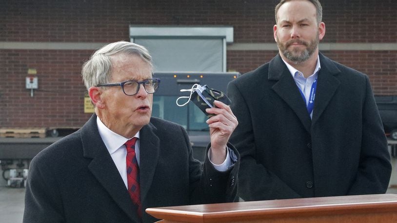 Gov. Mike DeWine reminds residents that they still need to wear a mask  as Springfield Regional Medical Center President Adam Groshans listens shortly after the first vaccine arrives at the hospital. BILL LACKEY/STAFF