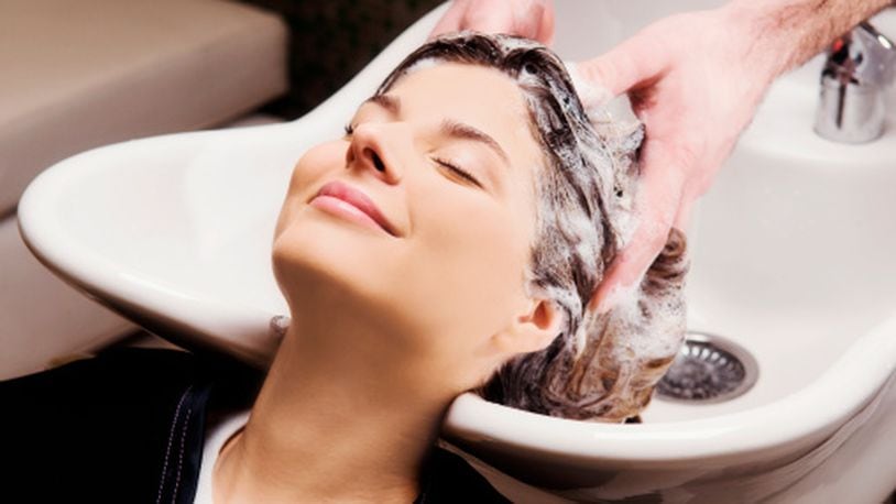 Young woman getting hair shampooed at salon