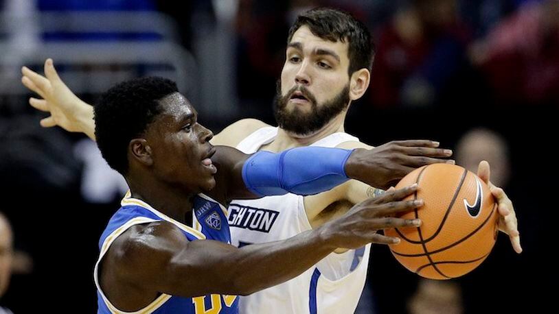 FILE- In this Nov. 20, 2017 file photo, Creighton's Manny Suarez, right, tries to block a pass by UCLA's Aaron Holiday, during an NCAA college basketball game in Kansas City, Mo. With one year of eligibility left, the 6-foot-10, 250-pounder Suarez transferred from Division II Adelphi to Division I Creighton, and he's playing a significant role off the bench. He's among fewer than 10 transfers who made the move from D2 to D1 this season. (AP Photo/Charlie Riedel, File)