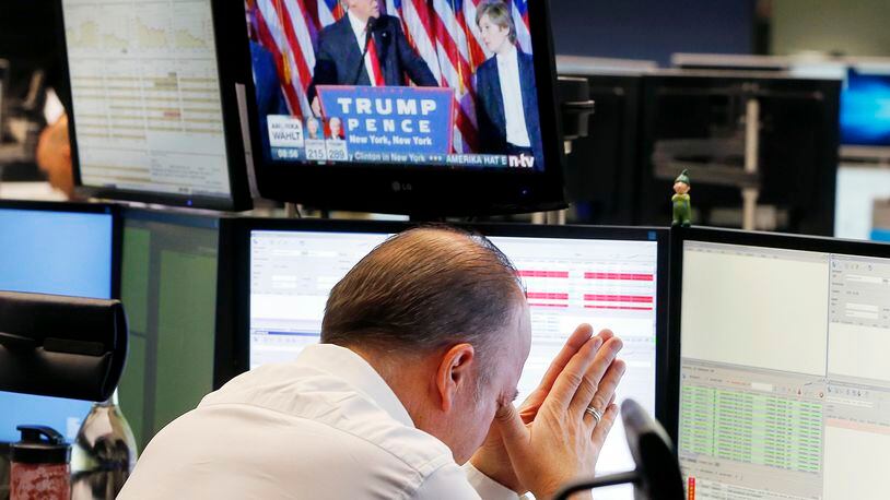 A broker reacts as new elected U.S. President Donald Trump shows up on a television screen at the stock market in Frankfurt, Germany, Wednesday. (AP Photo/Michael Probst)
