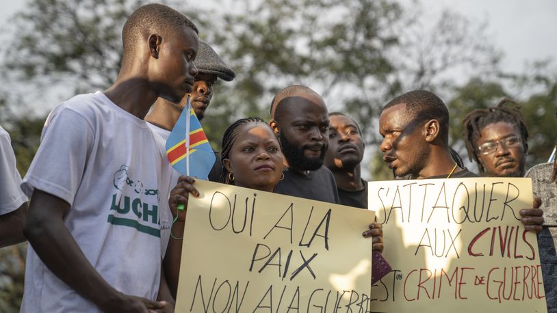 People gather in Goma, Democratic Republic of the Congo, Monday, May 6, 2024, to mourn the victims of the Mugunga Camp attack three days earlier. The signs read: 'Yes to peace, No to war' and 'Attacking civilians is a war crime.' (AP Photo/Moses Sawasawa)