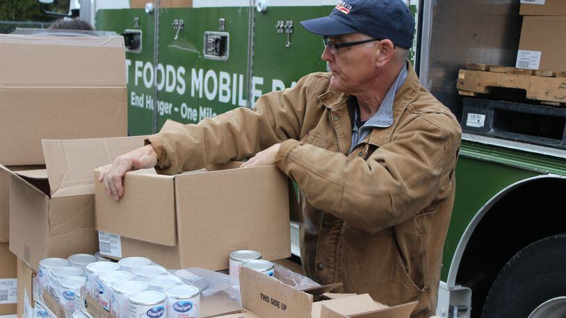 Mike Sherman of Second Harvest Food Bank opens boxes of food at the organization’s mobile pantry outside Rose’s department store on Derr Road. STAFF