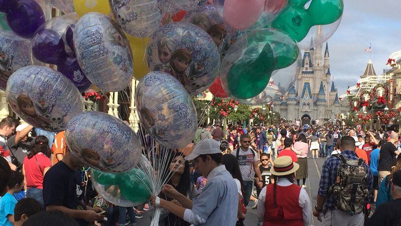 A Disney World employee sells balloons at the crowded Magic Kingdom park after Christmas. (Gabrielle Russon/Orlando Sentinel/TNS)