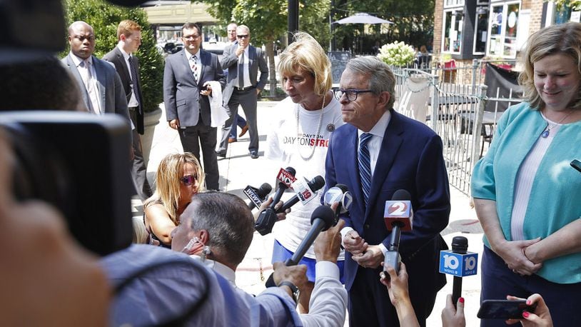 A security detail, top left, followed Governor Mike Dewine and Dayton Mayor Nan Whaley during a sidewalk press conference in the Oregon District on August 8. TY GREENLEES / STAFF