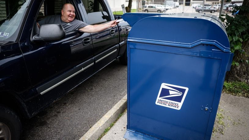 A resident pushes mail in the mailbox outside the postal office on Fifth St. in Dayton Wednesday May 18, 2022.A postal service key that unlocks all Dayton-area mailboxes was stolen recently, police records show. JIM NOELKER/STAFF