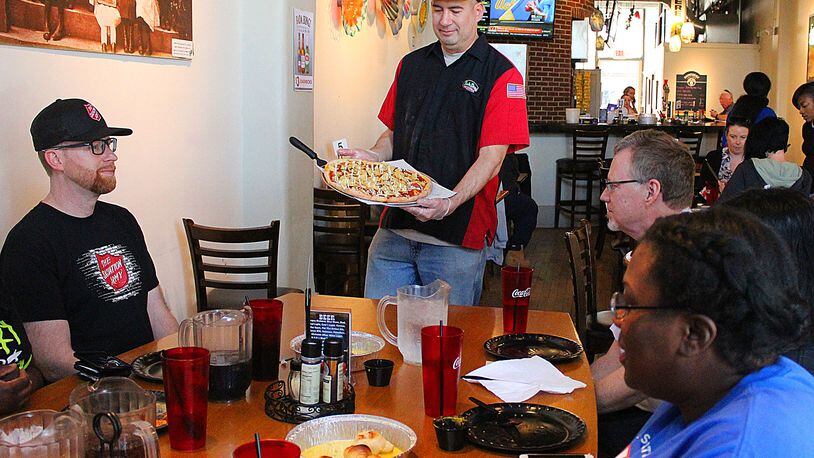 Bada Bing Pizzeria owner Jason Hague serves the staff of The Salvation Army a Red Kettle pizza.  The Red Kettle pizza is a special pizza that will be available during National Salvation Army week.  JEFF GUERINI/STAFF