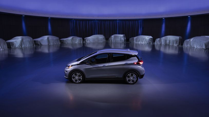 This photo provided by General Motors Co. shows a Chevrolet Bolt, surrounded by nine electric and fuel cell vehicles covered by tarps. Courtesy of GM via AP