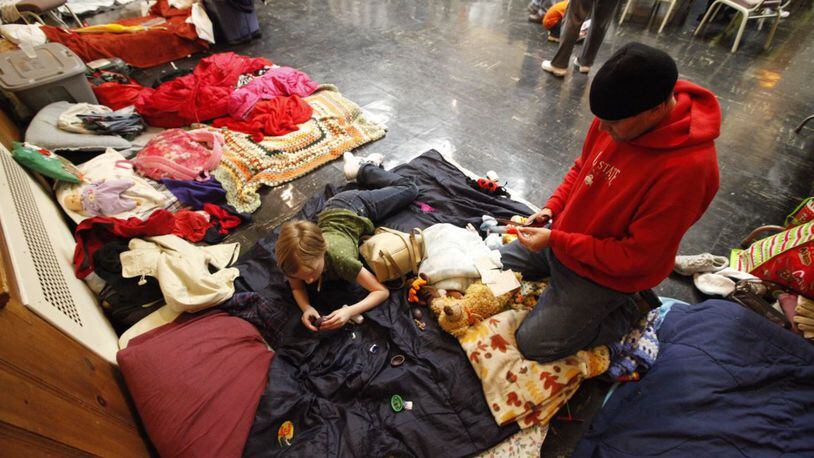 In this 2012 file photo, a homeless veteran and his daughter prepare to sleep on mats inside the SHALOM (Serving the Homeless with Alternate Lodging Of Middletown) shelter at the First Presbyterian Church in Middletown. STAFF/2012