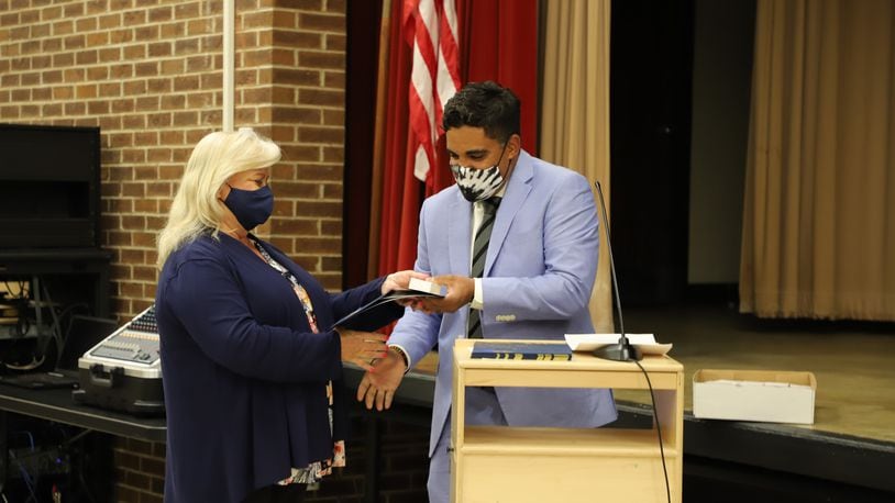 Huber Heights school Superintendent Mario Basora hands a certificate to district retiree Susan Harris.