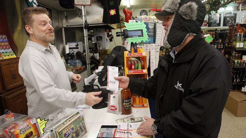 Michael Sliger, the manager of Bee-Gee's Market in Kettering (left) sells Mega Millions tickets to John Mott of Dayton Monday. Strong weekend Mega Millions ticket sales easily could push Tuesday's jackpot above last year's record $656 million prize, a lottery official said. No ticket matched the six numbers needed to win Friday's $425 million prize. It was raised Saturday to $550 million for Tuesday's drawing, the fourth largest in U.S. history. LISA POWELL / STAFF