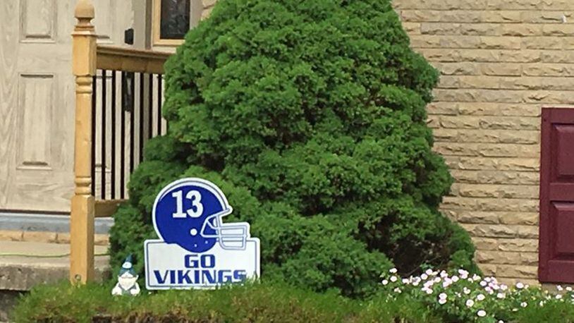 A sign outside Darren Hamblin’s home in Miamisburg shows his late son Cody’s No. 13 on a blue helmet. Hamblin’s lawsuit against helmet manufacturer Riddell is continuing in Montgomery County Common Pleas Court. STAFF