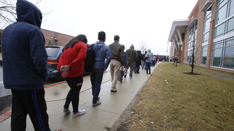 Members of a recently arrived family of refugees from Bhutan wait in a long line outside the Franklin County Department of Job and Family Services in Columbus, Ohio, on Wednesday, Feb. 21, 2018. The family can apply for various forms of government assistance, though their goal is to find work quickly. (AP Photo/Martha Irvine)