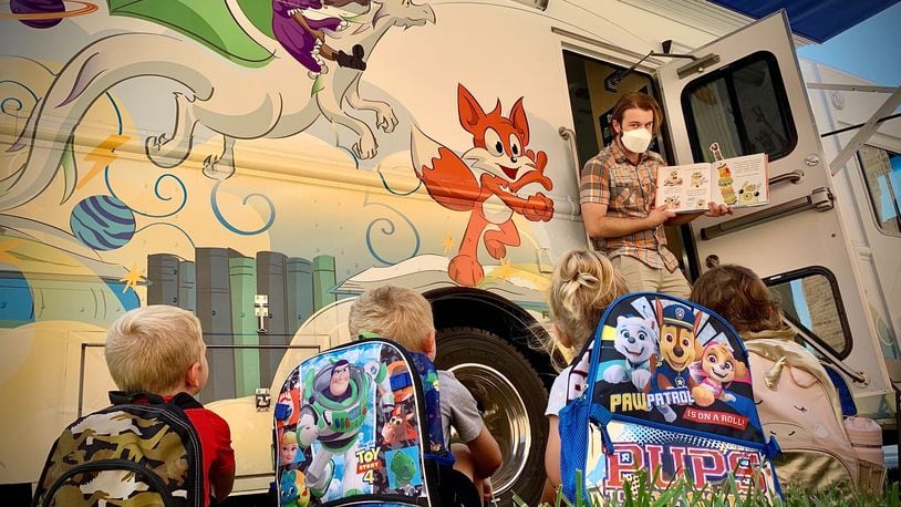 Cameron Chaney, bookmobile cleck, reads a story to Greene-View Elementary kindergarten students from the steps of the new Greene County Bookmobile, Tuesday Sept, 14, 2021. MARSHALL GORBY\STAFF